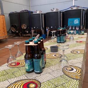 Cervezas artesanas en cata con equipo de fermentación en fondo industrial.